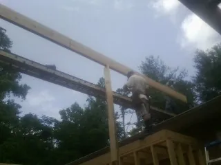 Carpenter setting a ridge beam over a new addition frame — Ice Dam Removal by Roofing Brothers in Buncombe