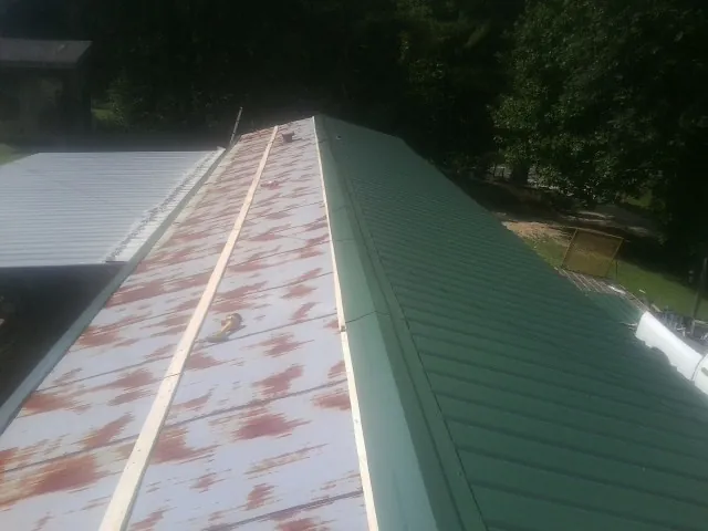 Old rusted panels beside newly installed green metal roofing — Wind Damage Roof Repair by Roofing Brothers in Buncombe