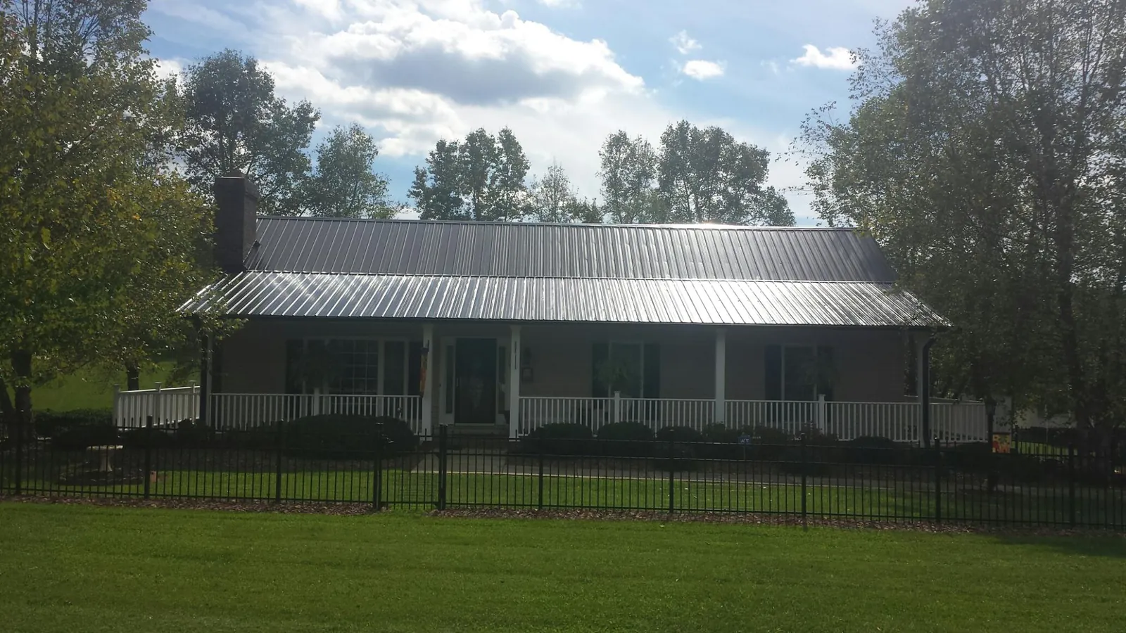 Gray metal roof on a brick ranch with a full width front porch — Gutter Guard Installation work by our crew in Buncombe