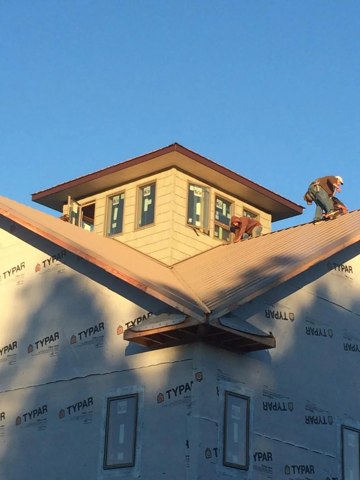 Roofers working around a rooftop cupola on a new metal roof at sunset — Roof Waterproofing in Buncombe by Roofing Brothers